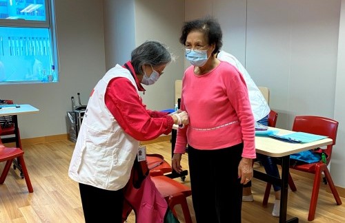 工王玉(左)為「健康自家管」長者慢性病管理服務的受惠者量度腰圍，評估他們的健康情況。